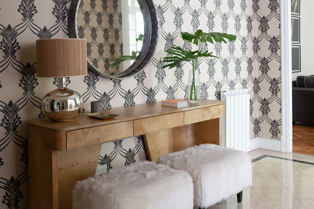 Foto de un hall con consola de cuero laqueado y banquetas de piel. Espejo diseñado por Rosario.