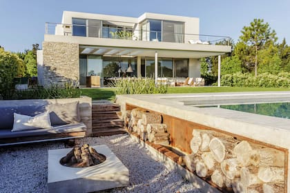 Foto de un jardín con con leñero a mano con fondo de chapa óxido sobre el lateral de la pileta.