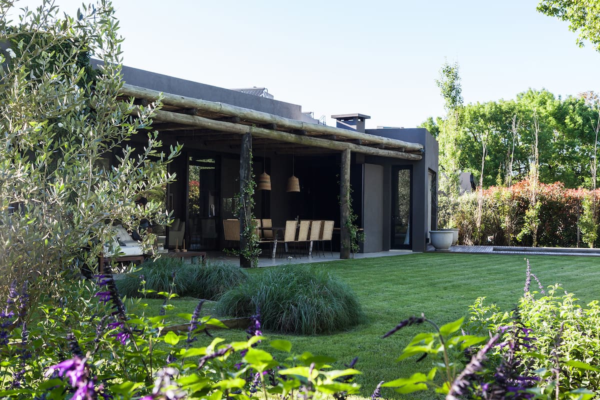 Foto de un jardín con pasto, plantas, galería y pileta.