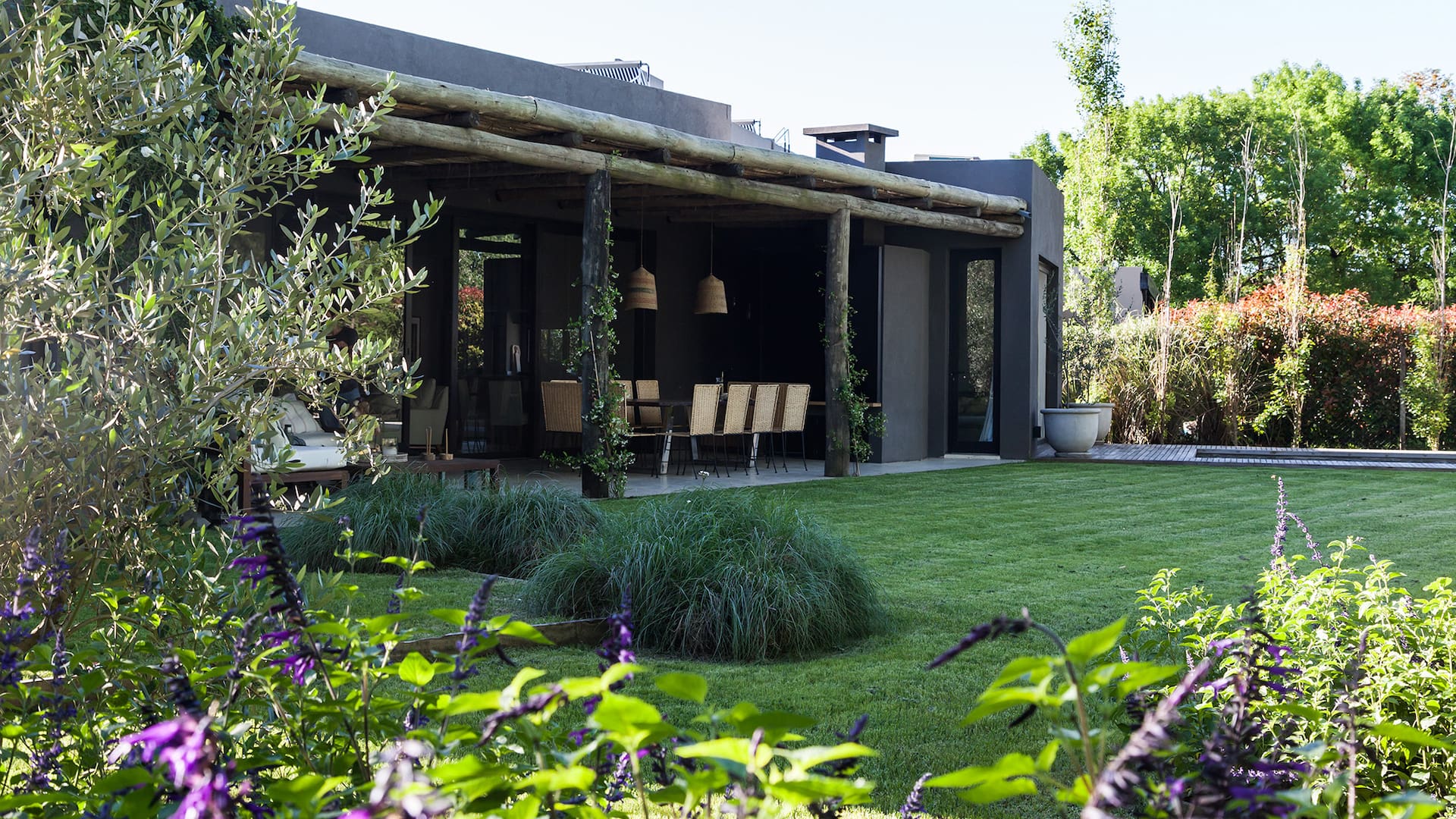 Foto de un jardín con pasto, plantas, galería y pileta.