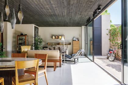 El living-comedor es una caja color arena con pisos de cemento alisado y cielo raso en madera quemada. Martín Moreno, el marido de Marina, se dedica a la fabricación de aberturas y fue el responsable de hacer las enormes puertas corredizas.