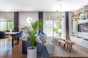 Foto de un living-comedor con sillón con funda de tussor, mesas bajas de madera paraíso y alfombra tejida a mano en telar.