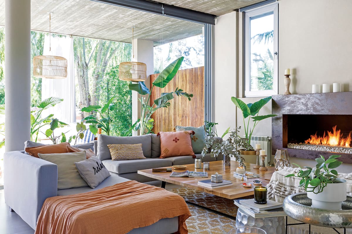 Foto de un living con almohadones, mesa de arrime y taburete color plata.