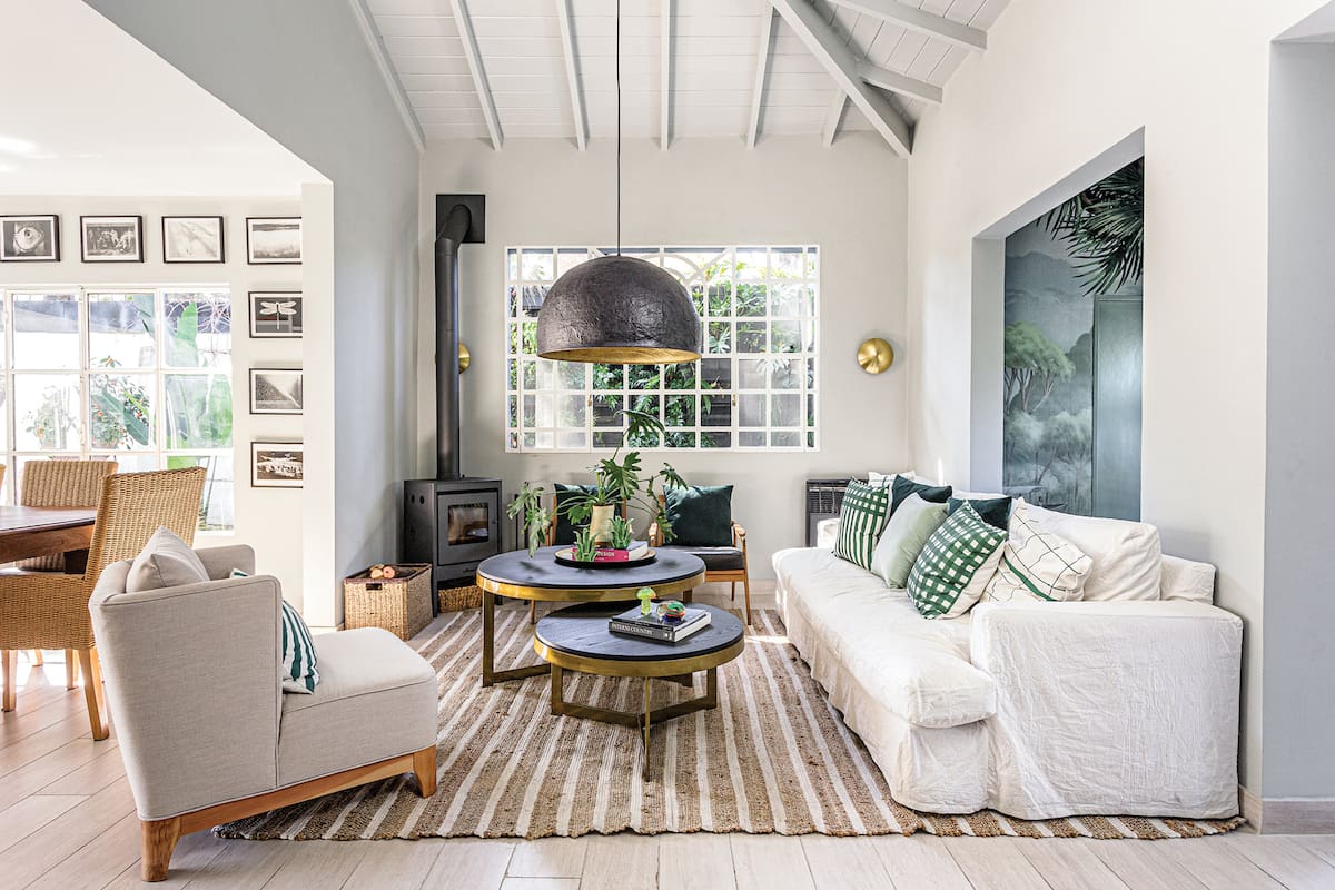 Foto de un living con chimenea, sillón blanco, mesas bajas y lámpara de techo.