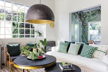 El verde se repite como patrón, acá en plantas, textiles y el mural.