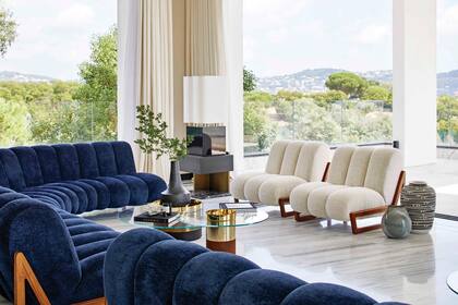 En una ambientación marcada por líneas rectas en superficies brillantes, las curvas aterciopeladas de los sillones modelo Theodore (Humbert & Poyet) invitan a contemplar el paisaje. Pisos en mármol ‘Bianco Lasa’, de veteado gris azulado.