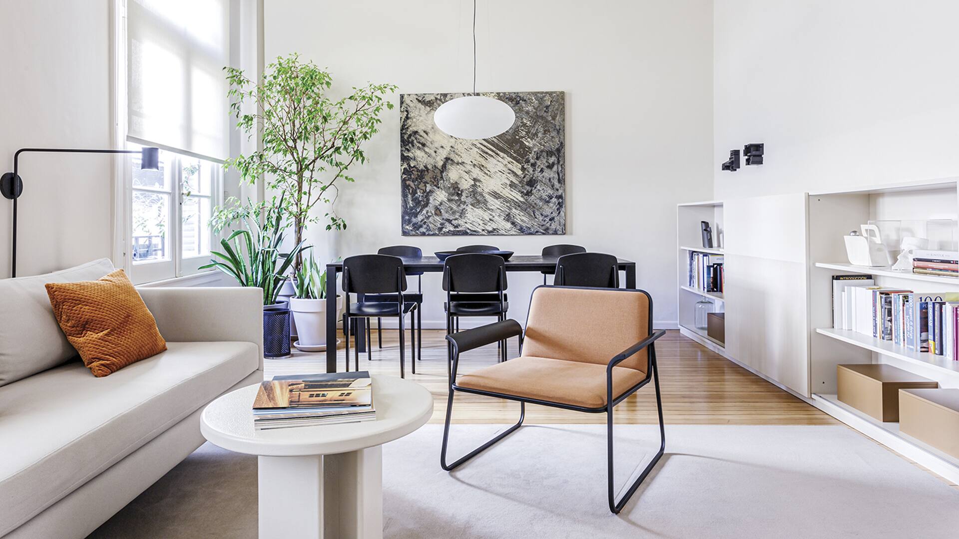 Foto de un living con poltrona, sofá, mesa circular y, al fondo, mesa de comedor.