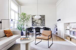 Foto de un living con poltrona, sofá, mesa circular y, al fondo, mesa de comedor.