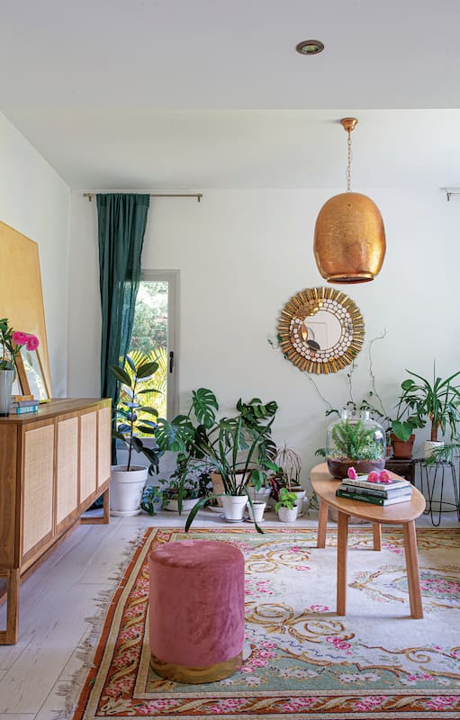 Foto de un living con sillones en color verde y salmón, lámpara colgante cobreada y mesa ratona.