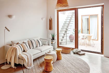 Sobre el sillón, almohadones comprados en Marruecos. Los taburetes de madera y la mesa de centro ‘Pebble’ en color cemento son del estudio de interiorismo catalán MIV Interiores.