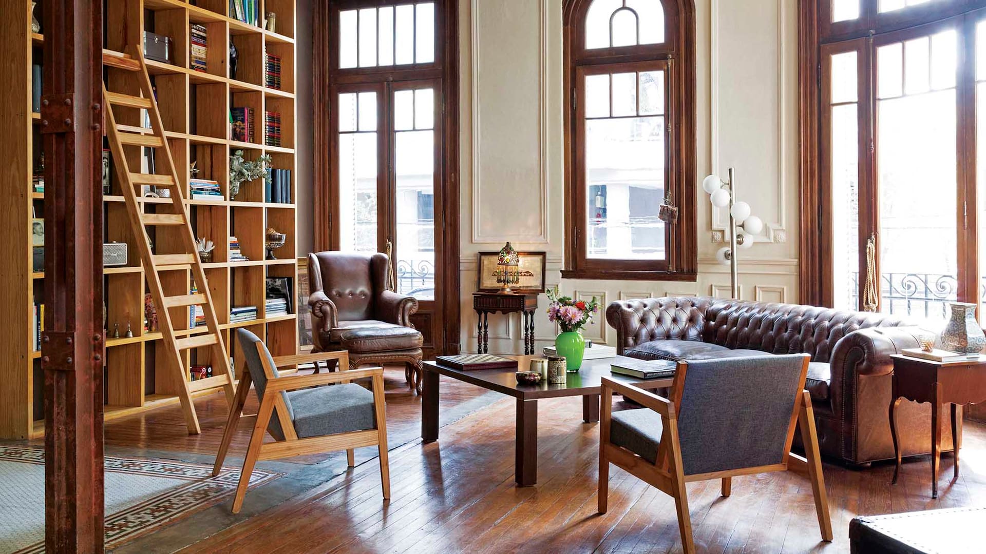 Foto de un living con sillón chester, biblioteca de piso a techo y piso de pino tea.