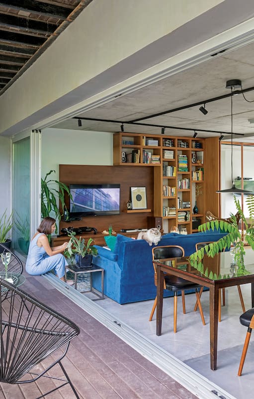 Foto de un living con sillón de pana azul, almohadones de pana verde y manta. Alfombra y mesas de apoyo y de centro.