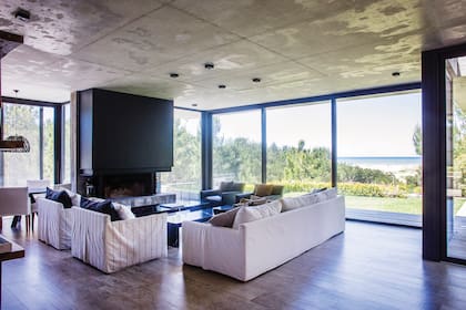 Sillones con fundas de tussor y mesas bajas de mármol (House of Surya). Chimenea revestida con placas cementicias (Superboard), abierta y a 50cm del suelo, por lo que el fuego se ve desde todos lados.