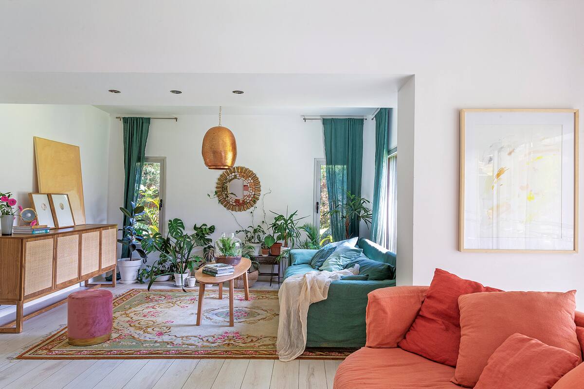 Foto de un living con sillones en color verde y salmón, lámpara colgante cobreada y mesa ratona.