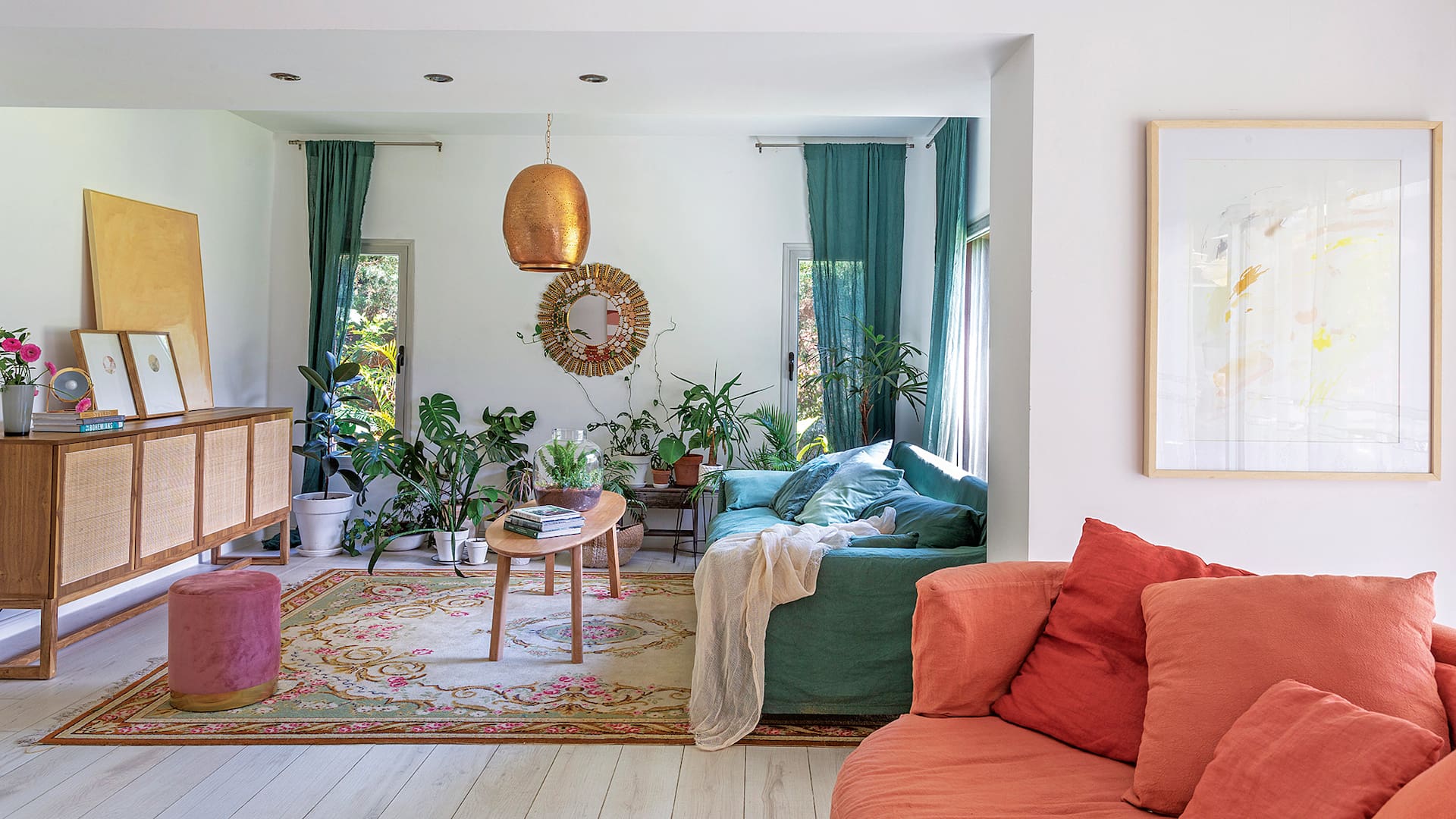 Foto de un living con sillones en color verde y salmón, lámpara colgante cobreada y mesa ratona.
