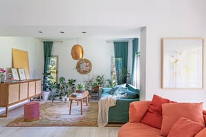 Foto de un living con sillones en color verde y salmón, lámpara colgante cobreada y mesa ratona.