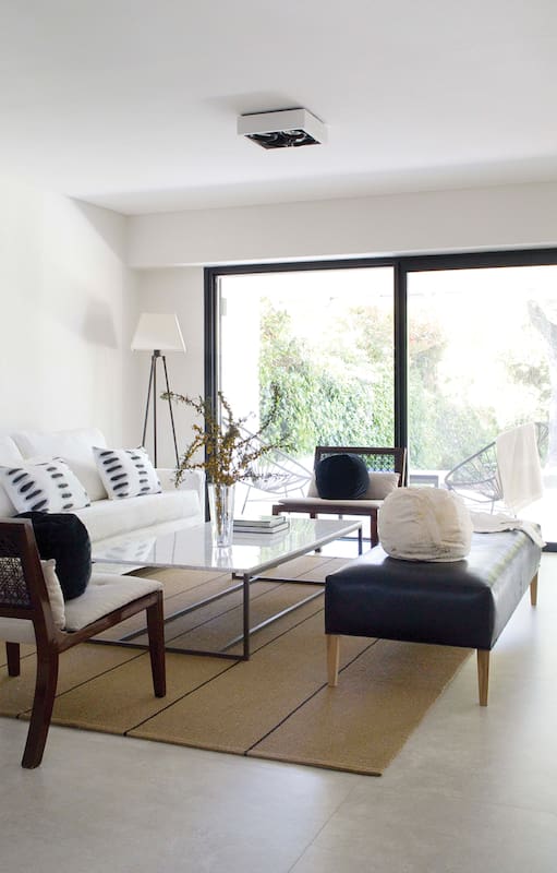Fotos de un living con chimenea y baco hecho en obra con almohadones y alfombra rayada.