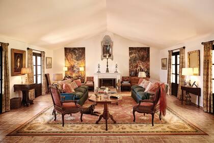 Los sofás ingleses, tapizados con un género verde petróleo de Marvic Textiles y decorados con almohadones estampados en rosa de Claremont. Lo que parecen ser tapices a cada lado de la chimenea son grandes impresiones en lino hechas por Zardi & Zardi y le dan un efecto cálido al ambiente.
