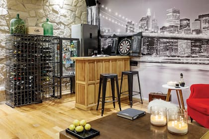 Cava, imagen ploteada en la pared, barra de madera, mesa de centro (Antigüedades El Viejo Taller). Banquetas ‘Tólix’ (JB Lacroux). Sillón ‘Berger’ heredado y retapizado en pana roja (Laura Bottinelli, de Art Capitoné). Velas (Bohemia Velas). Bandeja de mármol (Melgar Mármoles).