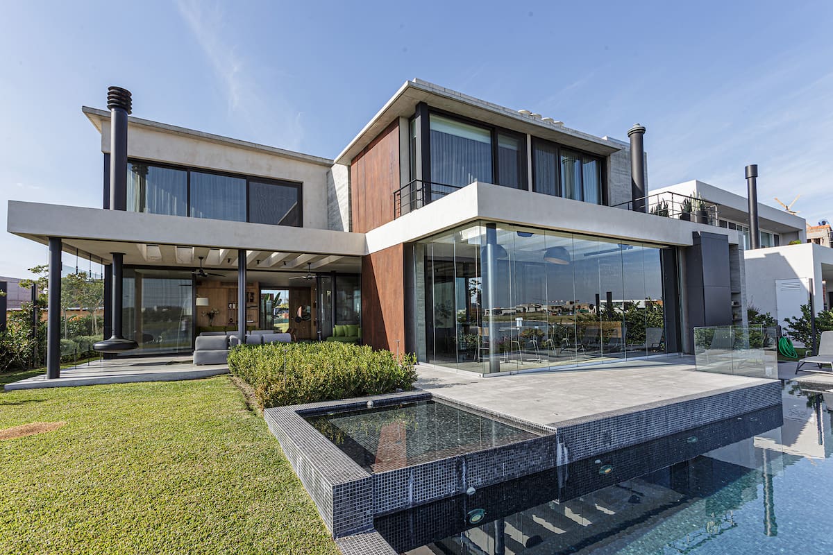 Foto de una casa con jardín, pileta y cerramiento de vidrio plegable.