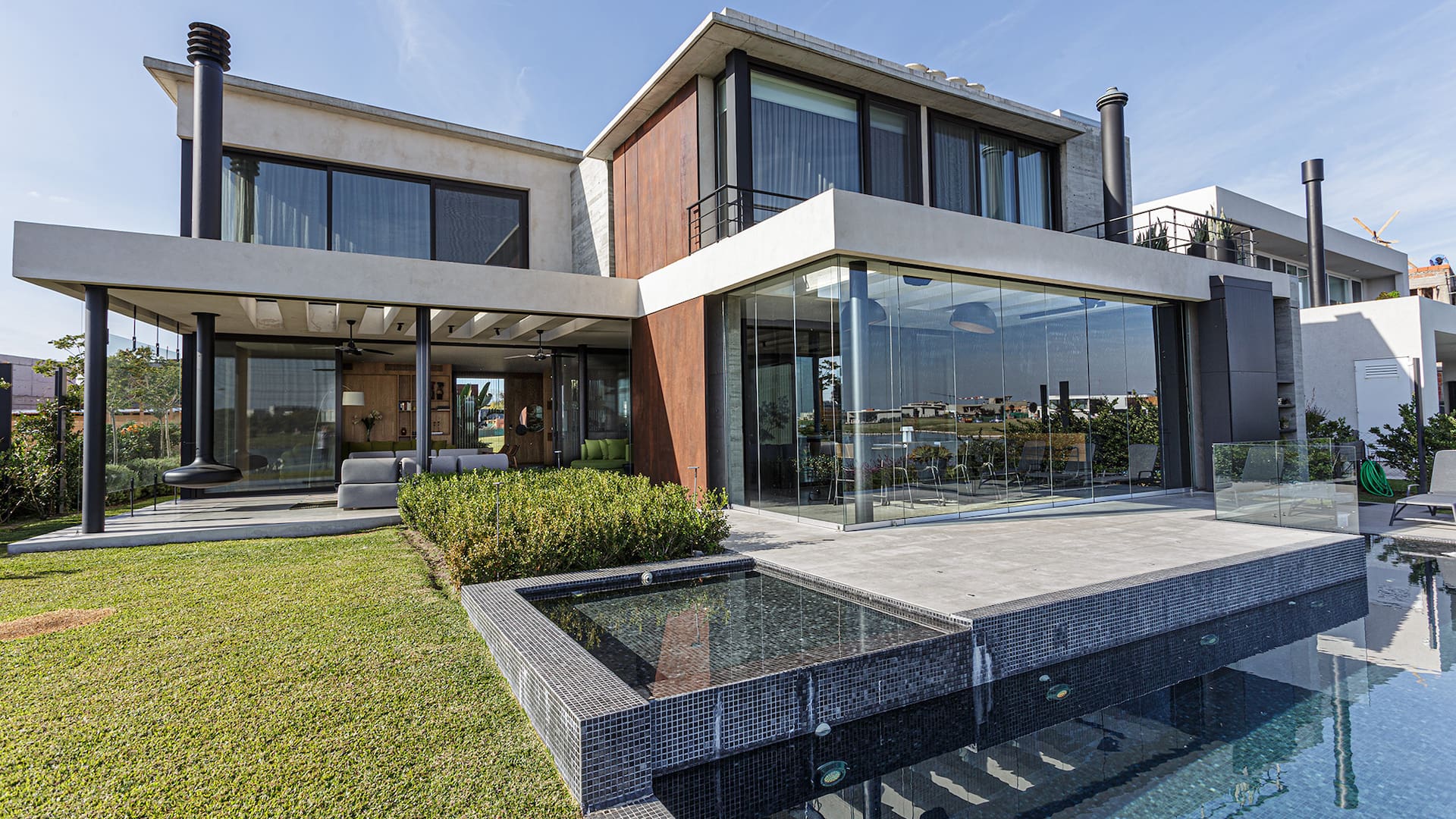 Foto de una casa con jardín, pileta y cerramiento de vidrio plegable.