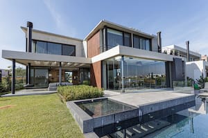 Foto de una casa con jardín, pileta y cerramiento de vidrio plegable.