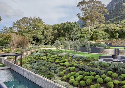Una escalera conecta un verde parque con el jardín de la casa.