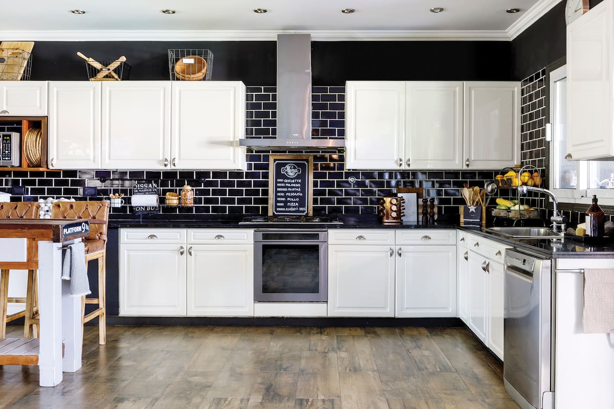 Foto de una cocina con cajas de madera, barral y panera, cartel de menú y especiero.