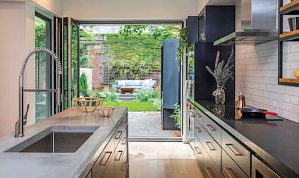 Antes, había dos ventanas en lugar de esta puerta-ventana plegadiza. Abrir la cocina al jardín aseguró luz, vista y metros para una distribución más eficiente.