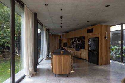 La isla es curva, con detalles en media caña de madera maciza. Tiene vidrio y sus patas se despegan del piso, lo que le da un aspecto visualmente liviano. El sector de la cocina fue realizado en Dekton Domoos, distribuido por Canteras del Mundo.