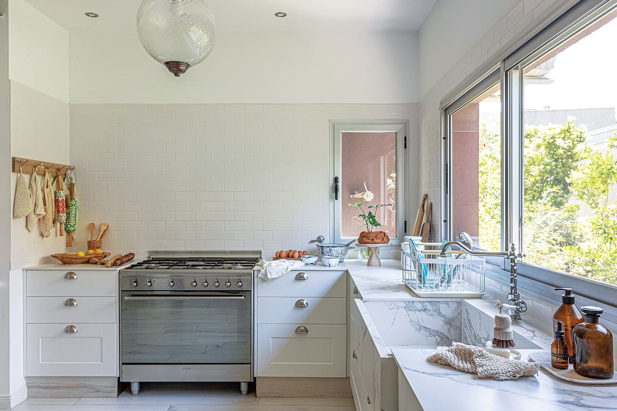 Foto de una cocina con lámpara de vidrio y muebles blancos.