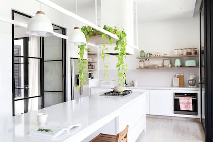 El amoblamiento fue diseñado y ejecutado por el estudio con madera laqueada, incienso lustrado y mesadas de Silestone ‘Blanco Norte’ en el mueble principal y la isla. Lámparas de techo ‘Nordic’ (Lumishop).