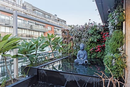 Un benéfico buda junto a una pared verde.