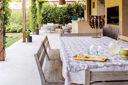 A un lado de la galería, el comedor al aire libre, con mesa de madera maciza y bancos con respaldo (Las Marinas). En el centro, la parrilla acompañada por una barra.