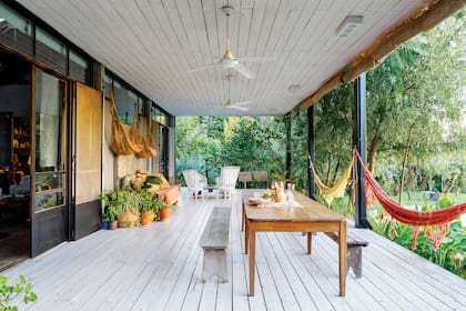 En la galería, mesa y banco de madera, dos hallazgos de Berna en una compraventa de la zona. Hamacas traídas de Brasil y ventiladores de techo (Martin & Martin).