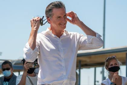 Foto del 4 de septiembre de 2021 del gobernador de California, Gavin Newsom, mientras se quita la mascarilla antes de hablar ante cientos de simpatizantes en un acto de campaña contra la votación revocatoria de California en Culver City, California. (AP Foto/Damian Dovarganes)