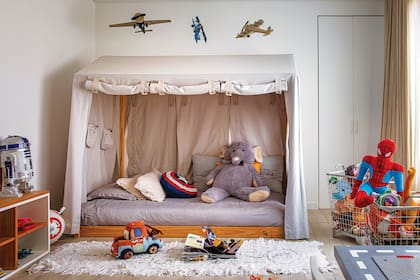 Aviones colgantes, elefante de peluche (Jumbo), cama con dosel (todo de Restoration Hardware), almohadones y alfombra ‘Rayuela’ (todo de Rancho).