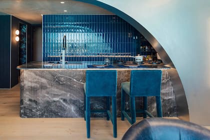 La barra, realizada en mármol facetado, toma inspiración de un desarrollo costero del estadounidense Felix Cohen, sumando un gesto escultórico y sofisticado. Banquetas 'Jirafa' (Estudio Leti Rocco).