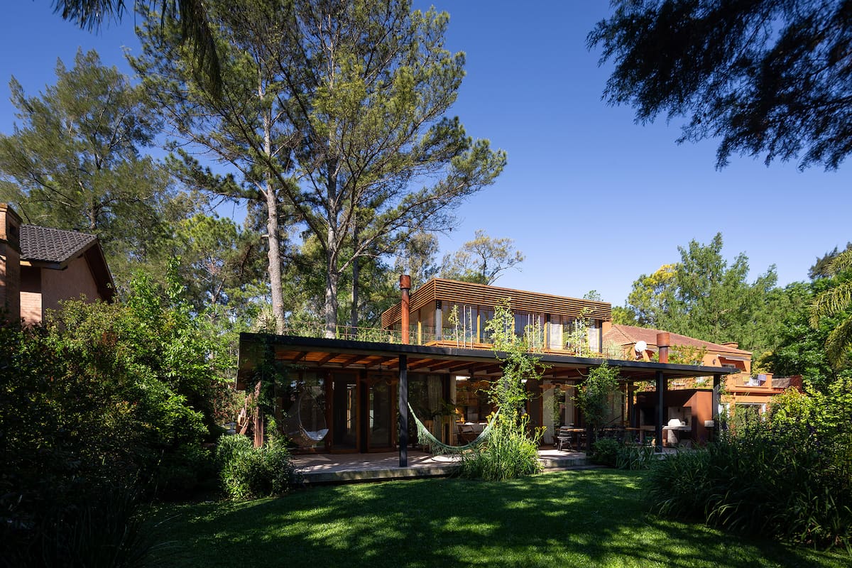 Foto del jardín de una casa con sector parrilla y hamacas.