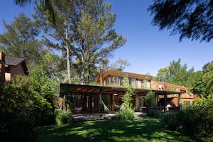 Foto del jardín de una casa con sector parrilla y hamacas.