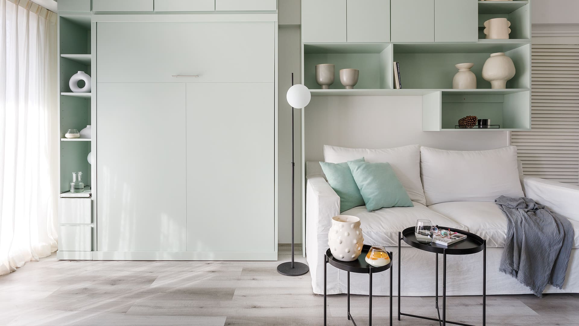 Foto del living de un monoambiente con mueble de pared, cama rebatible, y lámpara de pie (La Merced).