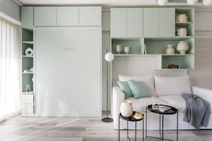 Foto del living de un monoambiente con mueble de pared, cama rebatible, y lámpara de pie (La Merced).