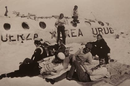Foto histórica de los sobrevivientes. Pancho Delgado, sentado en el techo del fuselaje, y Roberto Canessa (de pie), tejen tela aislante. Recostados: Fito Strauch, Carlitos Páez, Gustavo Zerbino, Eduardo Strauch, Nando Parrado y Javier Methol.