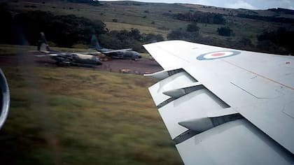 Foto tomada a finales de abril de 1982 desde la ventanilla de un VC10 C1 del Escuadrón N.º 10 a punto de despegar, esta fotografía inédita muestra un Hercules C1 del Escuadrón N.º 30, con sus insignias de la RAF pintadas, en la Isla de Pascua junto a un C-130 de la Fuerza Aérea de Chile (el más cercano de los dos Hercules). La aeronave británica fue desplegada en apoyo a la Operación ‘Folklore’. La autoría de la foto es adjudicada al líder de escuadrón BILL RAGG