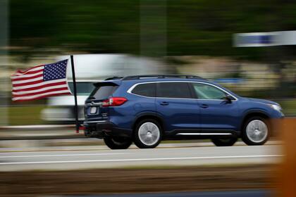 Fotografía de archivo del 28 de mayo de 2021 de un conductor de Massachusetts ondeando una bandera estadounidense mientras recorre la Maine Turnpike en Kennebunk, Maine. (AP Foto/Robert F. Bukaty)