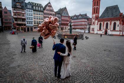 Fotografía de archivo del 5 de marzo de 2021, de una pareja posando en la plaza Roemerberg después de casarse en Fráncfort, Alemania, cuando debido a la pandemia de coronavirus estaban prohibidas las fiestas de boda. (AP Foto/Michael Probst)