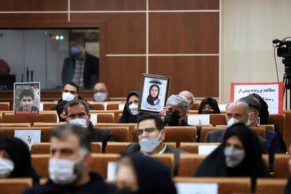 Fotografía difundida por la agencia de noticias Mizan de personas sosteniendo retratos de seres queridos que murieron en el derribo de un avión ucraniano en 2020 que mató a 176 personas durante una audiencia en un tribunal militar iraní el domingo 21 de noviembre de 2021 en Teherán, Irán. (Koosha Mahshid Falahi/Mizan News Agency vía AP)