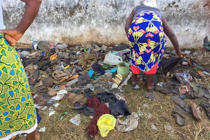 Fotografía proporcionada por Augustine D Wallace de una mujer buscando entre zapatos el jueves 20 de enero de 2022 en un campo donde se confirmó la muerte de 29 personas luego de una estampida en las afueras de Monrovia, Liberia, el miércoles por la noche. (Augustine D Wallace vía AP)