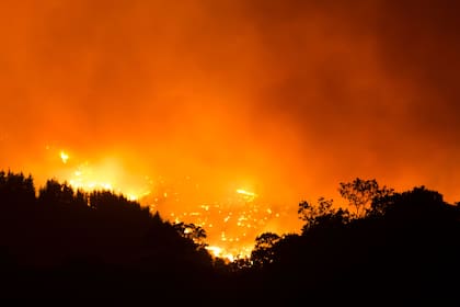 Fotografía tomada desde el pueblo de Cartajima muestra las llamas de un incendio forestal, que estalló hace tres días, quemando un área de bosque detrás del pueblo de Pujerra el 12 de septiembre de 2021