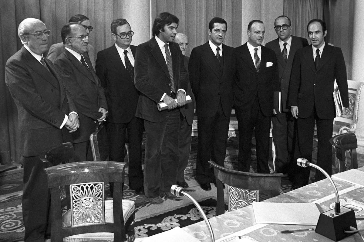 Fotografía tomada durante la firma de los Pactos de la Moncloa en 1977, en la que aparecen los representantes de los grupos parlamentarios. De izquierda a derecha, Enrique Tierno Galván (PSP), Santiago Carrillo (PCE), José María Triginer (Federación catalana PSOE), Joan Raventos (PSC), Felipe González (PSOE), Juan Ajuriaguerra (PNV), Adolfo Suárez (UCD), Manuel Fraga Iribarne (AP), Leopoldo Calvo Sotelo (UCD) y Miquel Roca (Minoría Catalana).